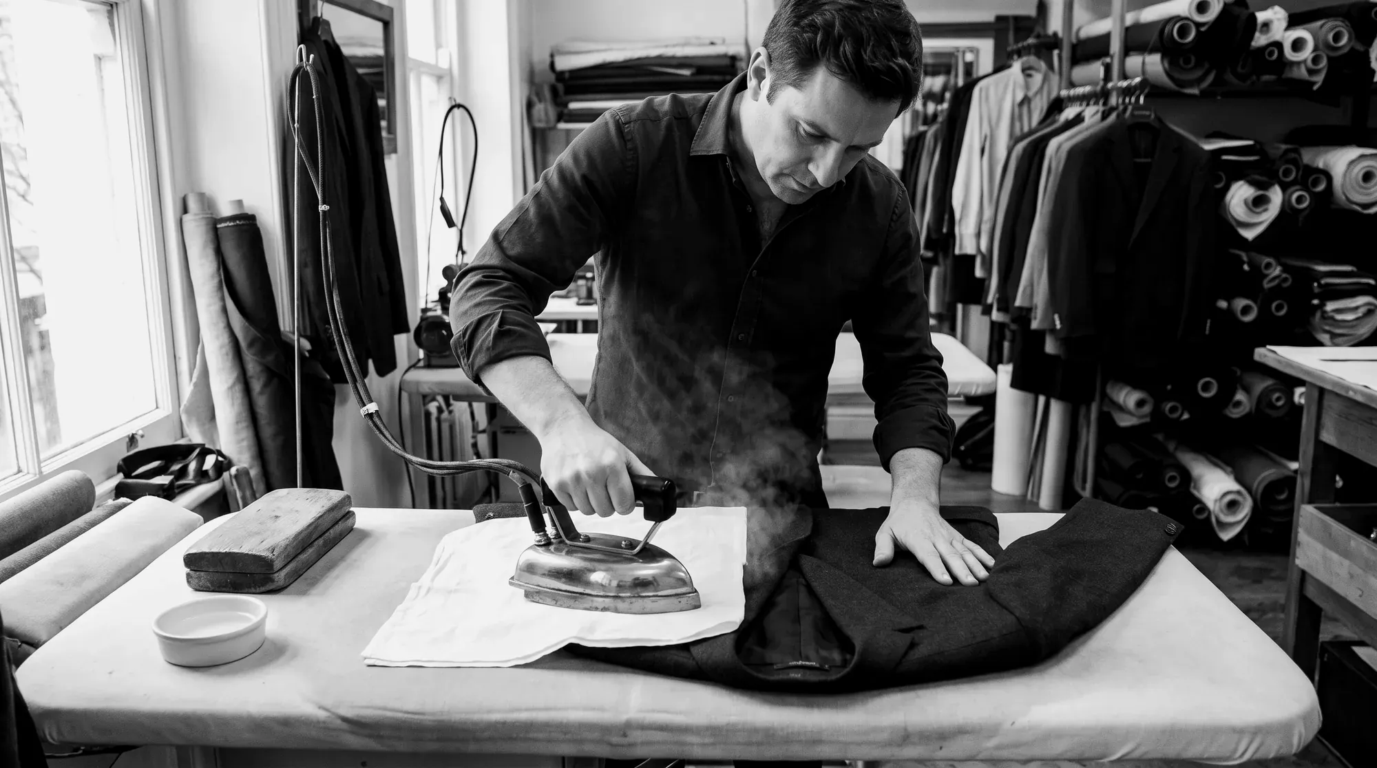 Tailor pressing a jacket with a steam iron